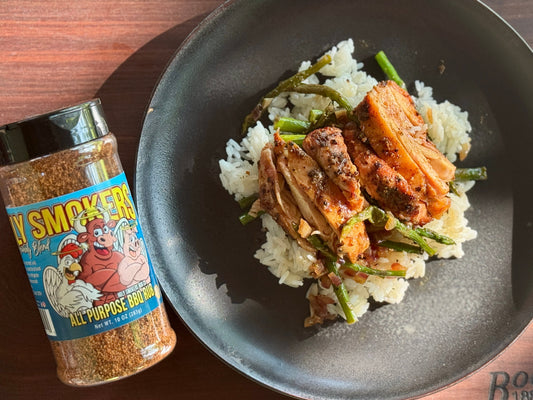 Smoked boneless skinless chicken thighs seasoned with Holy Smokers AP Rub, served over coconut aminos rice with steamed asparagus on a clean plated bowl, showcasing a healthy, smoky, and savory BBQ-style meal.