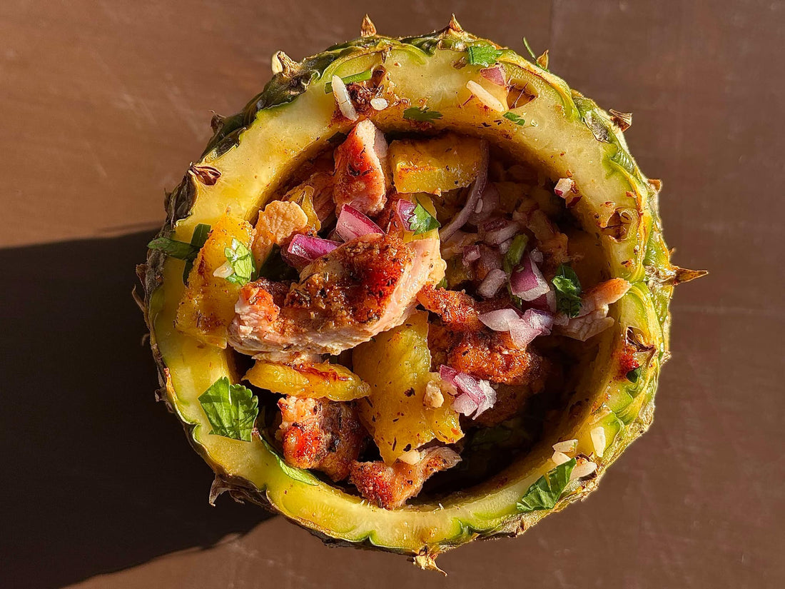 Caribbean jerk chicken bowl featuring grilled, smoky jerk-seasoned chicken thighs served over jasmine rice with caramelized pineapple and fresh pico de gallo, showing a vibrant tropical dish with sweet, spicy, and savory elements.