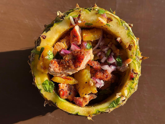 Caribbean jerk chicken bowl featuring grilled, smoky jerk-seasoned chicken thighs served over jasmine rice with caramelized pineapple and fresh pico de gallo, showing a vibrant tropical dish with sweet, spicy, and savory elements.